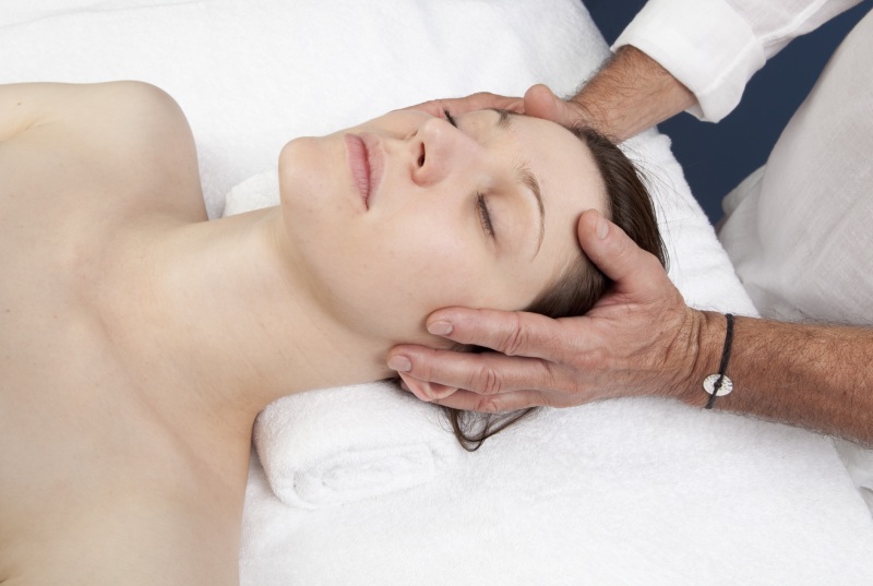 Woman lying down receiving a face massage by a physical therapist