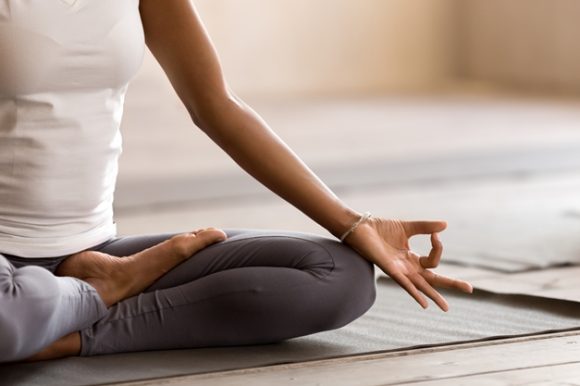 Woman doing yoga on a yoga mat sitting in a meditative position